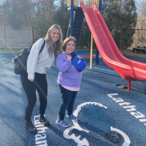 Staff at Latham Centers welcomes new student on her first day and shows her the Latham campus playground.