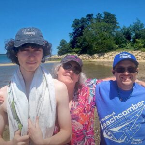 Shared Living Living Resident poses for photo at beach with his Shared Living family.