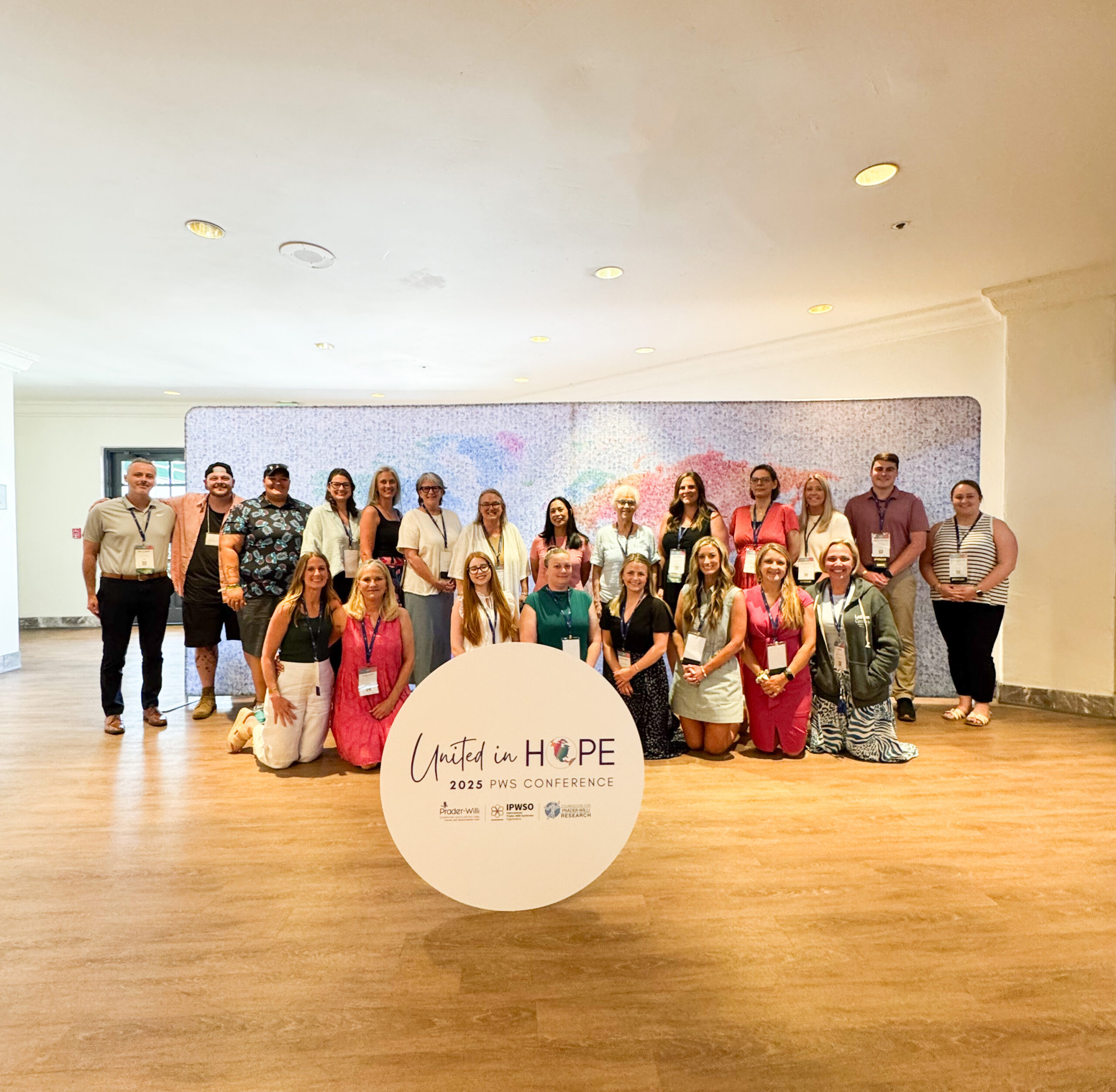 Group of people standing in front of map with a united in hope sign in front