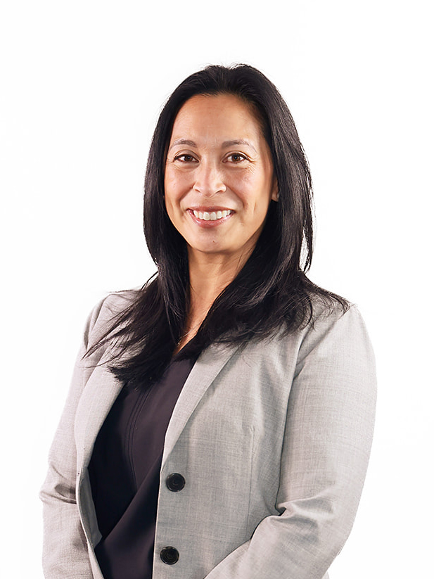 Woman standing wearing gray suit jacket, formal.